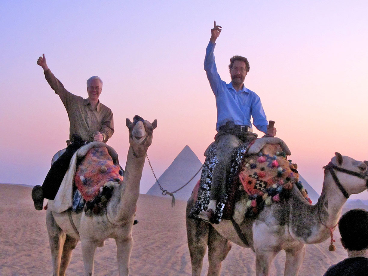 Banning Eyre ’79 (l) and Sean Barlow ’79 (r) enjoy a post-concert camel ride at sunrise, guests of Egyptian superstar Hakim.
